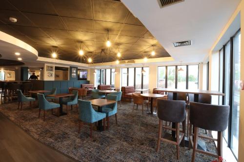 a restaurant with tables and chairs and windows at Knowsley Inn & Lounge formally Holiday Inn Express in Knowsley