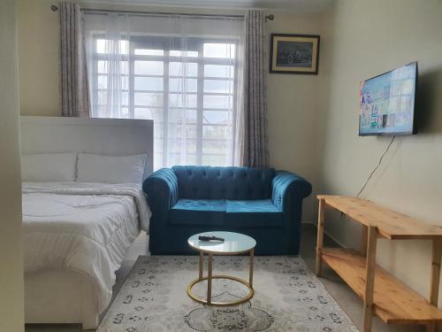 - une chambre avec un canapé bleu, un lit et une table dans l'établissement Regional Homes, à Syokimau