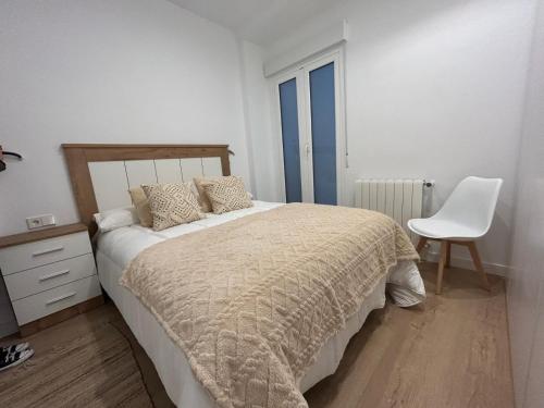 1 dormitorio con 1 cama y 1 silla blanca en Churruca apartment with terrace, en San Sebastián