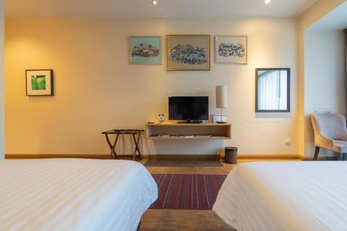 a hotel room with two beds and a flat screen tv at Rimkhobfa Urban Resort in Samutprakarn