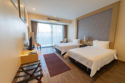 a hotel room with two beds and a large window at Rimkhobfa Urban Resort in Samutprakarn