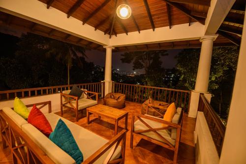 a porch with chairs and a table and a table and chairs at Kingsman House in Kandy