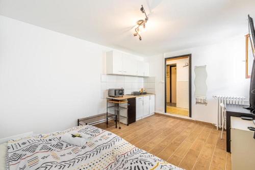 Cette chambre blanche dispose d'un lit et d'une cuisine. dans l'établissement Cénoslocs Aulnay - Studio atypique proche de l'aéroport CDG, à Aulnay-sous-Bois