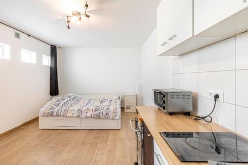 - une cuisine avec un lit dans une chambre aux murs blancs dans l'établissement Cénoslocs Aulnay - Studio atypique proche de l'aéroport CDG, à Aulnay-sous-Bois
