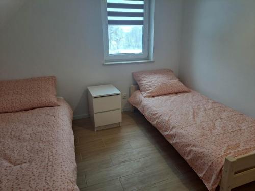 a small bedroom with two beds and a window at Słoneczna Sielanka domki w Bieszczadach in Ustrzyki Dolne