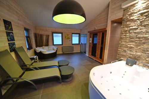 a living room with chairs and a table and a stone wall at Gite Fond des Vaulx in Marche-en-Famenne