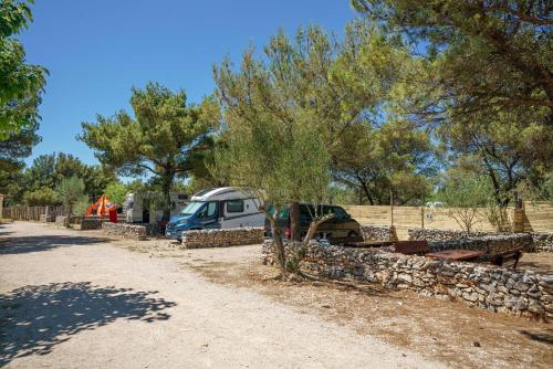 a campsite with a car parked next to a stone wall at Camping Vrata Krke in Lozovac