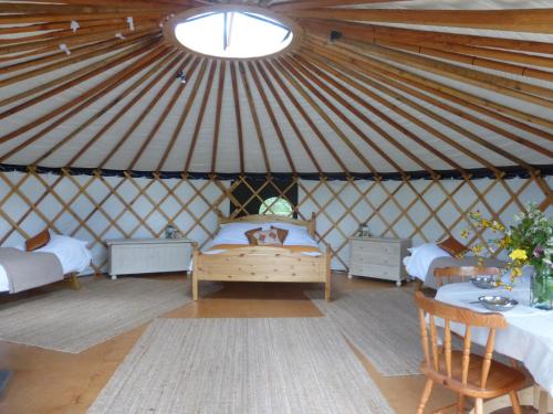 a room with a bed and tables in a yurt at Chestnut Yurt in Fernhurst