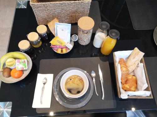 una mesa de desayuno con un plato de comida y un plato de pan en TUILERIE DE LA COTE 4*, en Ouzouer-sur-Trézée