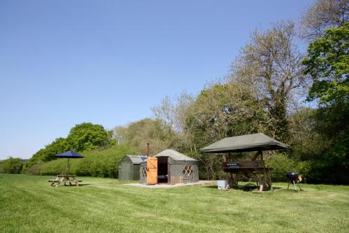 a park with a tent and a grill and picnic tables at Beech Yurt in Fernhurst