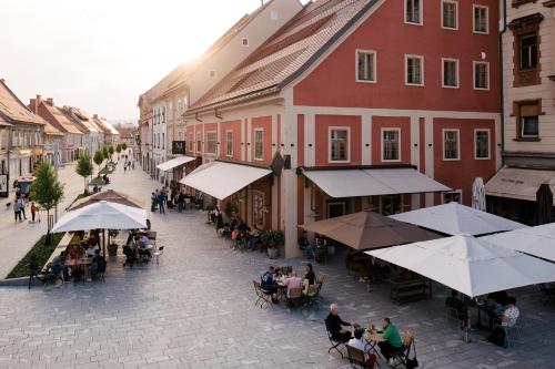 a group of people sitting at tables in a street with buildings at Hotel Maribor, City apartments in Maribor