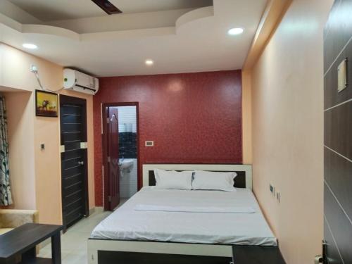 a bedroom with a bed and a red wall at HOTEL SANDSTONE INTERNATIONAL in Kolkata