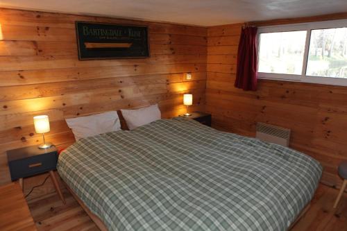a bedroom with a bed in a room with wooden walls at Péniche Kairos - Havre de paix sur Canal du midi in Toulouse