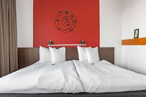 a large bed with white sheets and a red wall at Best Western Malmia Hotel in Skellefteå