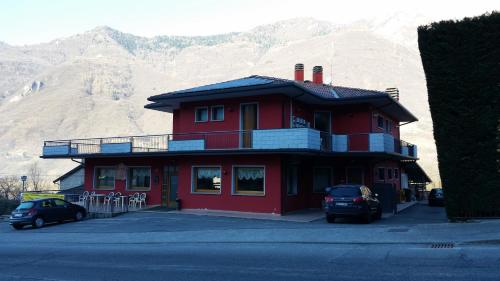 a red building with cars parked in front of a mountain at B&B La Villetta in Niardo