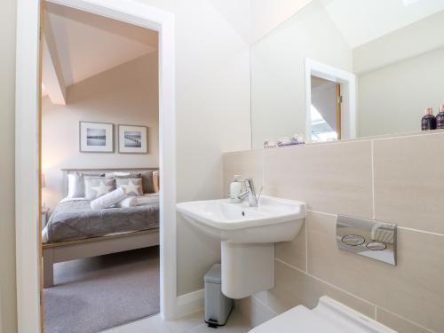a white bathroom with a sink and a bed at Sandy House in Rhosneigr