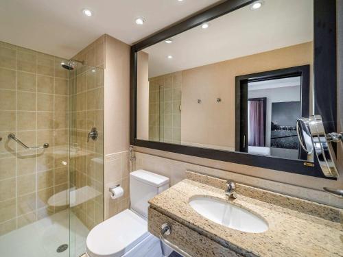 a bathroom with a toilet and a sink and a shower at Novotel SP Jardins in São Paulo