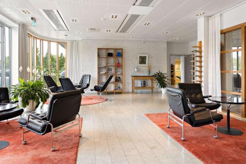 a lobby with chairs and a table and a fireplace at First Hotel Planetstaden in Lund