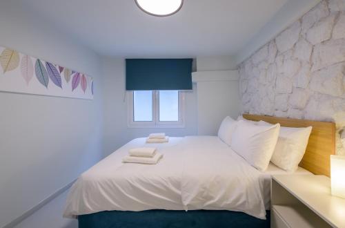 Fully renovated underground flat in Pagrati في أثينا: غرفة نوم بسرير ابيض عليها مناشف