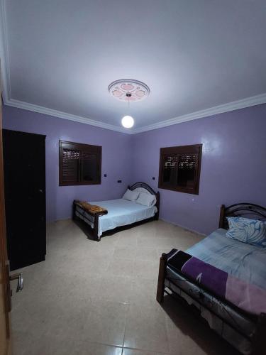 - 2 lits dans une chambre aux murs violets dans l'établissement RESIDENCE ABOU YASSINE, à Dakhla