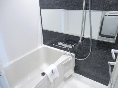 a bathroom with a bath tub with a shower at HOTEL LiVEMAX PREMIUM Nagoya Marunouchi in Nagoya