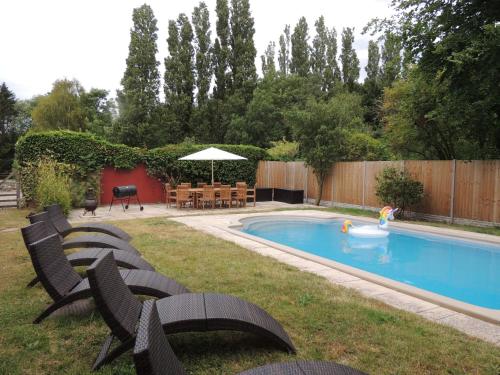 a backyard with a swimming pool with chairs and a table at The Landers in Cheltenham