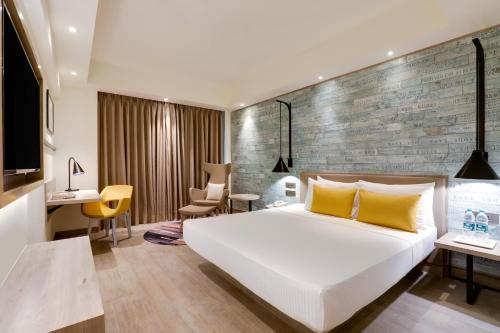 a bedroom with a large white bed and a brick wall at Lemon Tree Premier, Mumbai International Airport in Mumbai