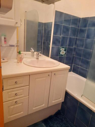 La salle de bains est pourvue d'un lavabo et d'un mur carrelé bleu. dans l'établissement Appartement T2 vue Mer et Port,2 balcons, Parking privé, à Canet