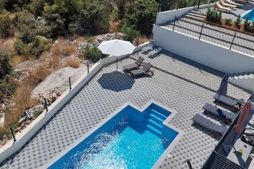 uma vista sobre uma piscina com um guarda-sol e cadeiras em Apartment Vista Oasis with Pool and Terrace em Trogir