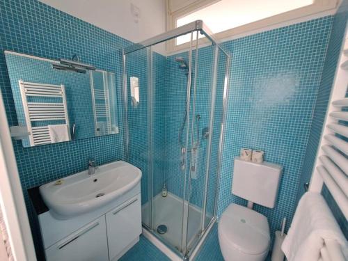 y baño de azulejos azules con aseo y ducha. en Le Casasse Vico Delle Stelle, en Varigotti