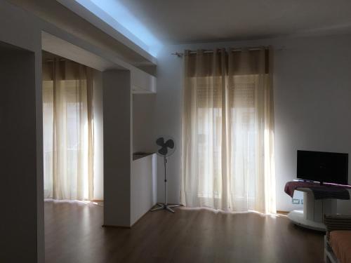 a room with white curtains and a room with a television at Casa Baby Planet in Scicli