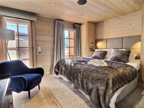 a bedroom with a large bed and a blue chair at Chalet Les Gets, 7 pièces, 12 personnes - FR-1-627-6 in Les Gets