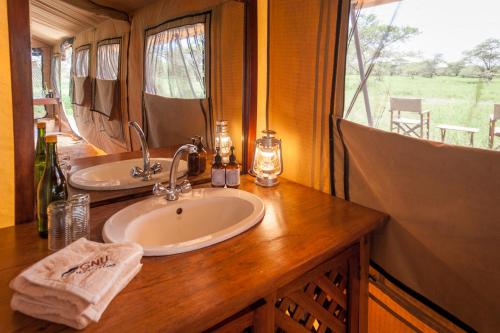 een badkamer met een wastafel en een spiegel bij Gnu Ndutu Camp in Sinoni