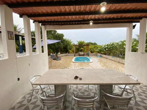a patio with a table and chairs and a pool at Casa Enseada dos Corais in Cabo de Santo Agostinho