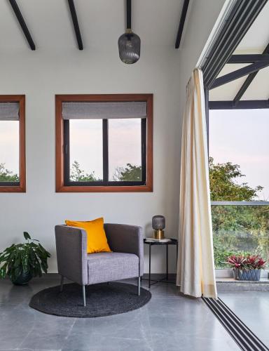 a living room with a chair and a window at SaffronStays Ahilya Waters by Kosha Villas, Pawna - pool villa with panoramic view of Pawna Lake in Āmbavna