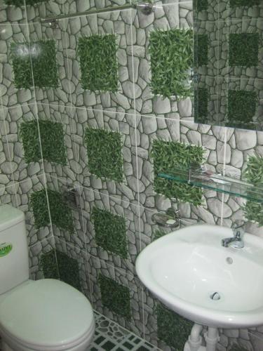 a bathroom with a toilet and a sink with a stone wall at Hai Long Vuong Hotel in Da Lat