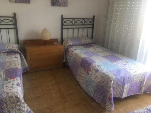 um quarto com 2 camas e uma mesa com um candeeiro em ÁTICO-DUPLEX EN URB. PEÑISMAR en 1ª línea de playa em Peníscola