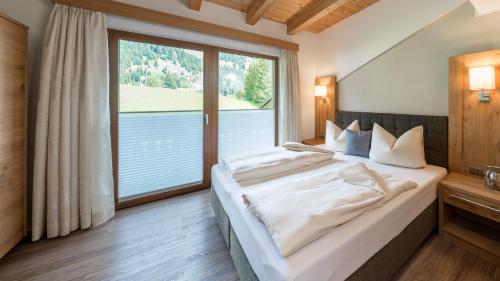 a bedroom with a bed and a large window at BIRKENHOF - Premium Apart & Suites in Lermoos