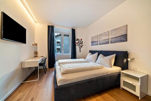 a bedroom with a bed and a desk and a television at Central Suite Meran in Merano