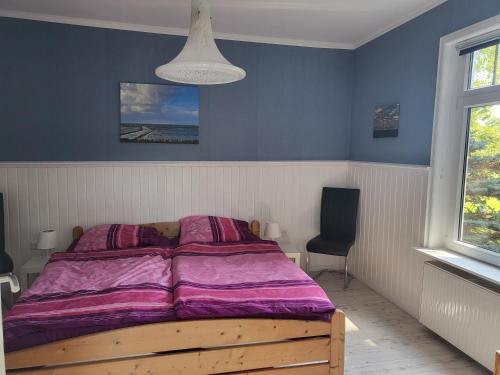a bed with a purple comforter in a bedroom at Urlaub im blauen Haus in Sehestedt