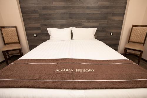 a bedroom with a large bed with two chairs at Alaska Resort in Tsaghkadzor