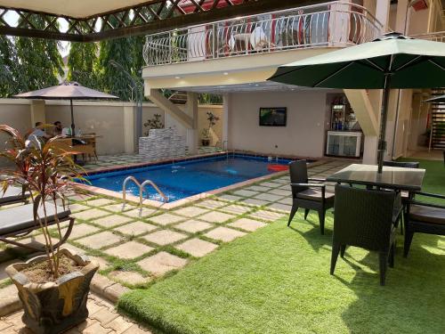 a swimming pool with a table and an umbrella at J's Place in Abuja