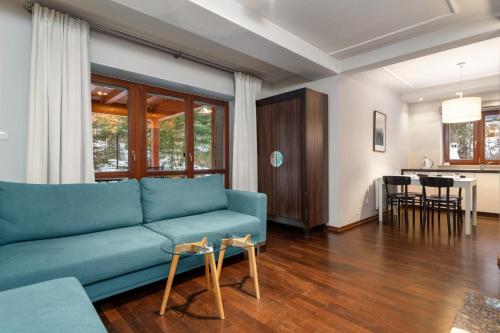 a living room with a blue couch and a kitchen at RentPlanet - Śpiący Rycerz in Zakopane