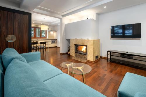 ein Wohnzimmer mit einer blauen Couch und einem Kamin in der Unterkunft RentPlanet - Śpiący Rycerz in Zakopane