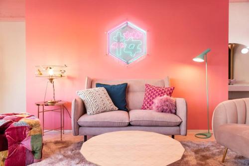 uma sala de estar com um sofá e uma parede rosa em Moshi Moshi Rooms em Tóquio