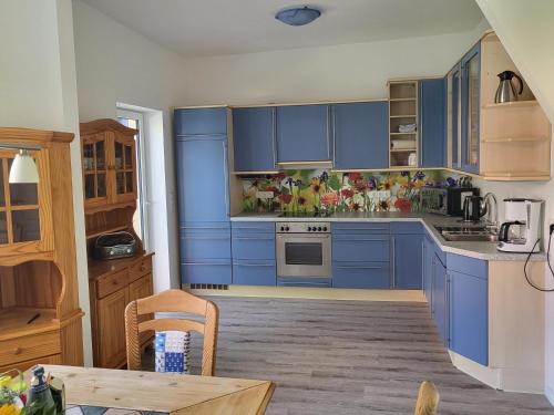 a kitchen with blue cabinets and a table at Urlaub im blauen Haus in Sehestedt