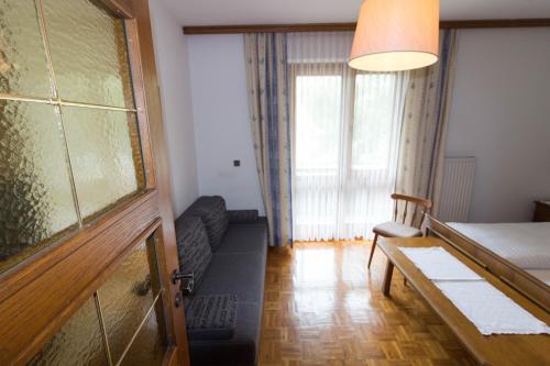 a room with a bed and a couch and a window at Ferienhof Alte Post, Apartments in Weissbriach