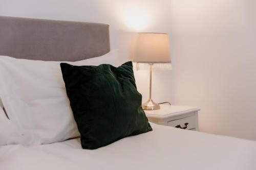 a bed with a green pillow and a lamp on a table at La Fontaine in Hunedoara