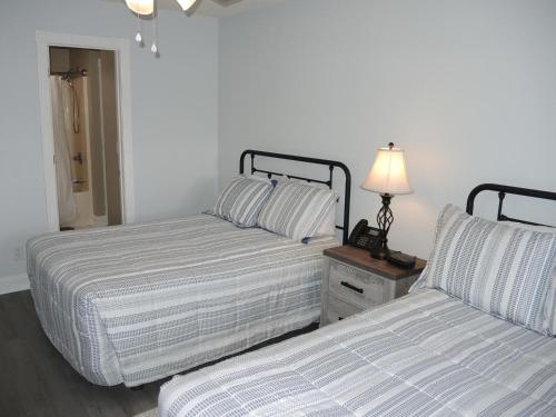 - une chambre avec 2 lits et une lampe sur une table de chevet dans l'établissement Brunswick Plantation 302M Golf Villa, à Calabash