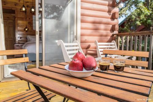 a bowl of pomegranates on a wooden table on a porch at Vibe Naftali Estate in Ramot Naftali